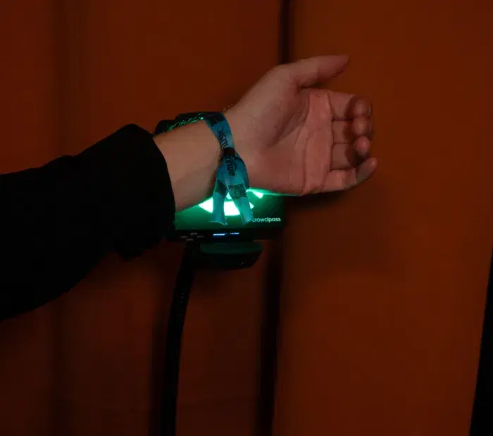 Attendee scanning RFID wristband on CrowdReader with green access granted indicator